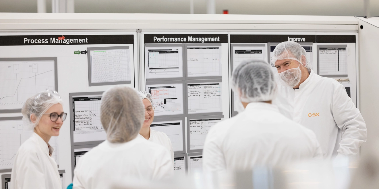 Cinq scientifiques discutent devant un tableau où sont notés les performances et processus