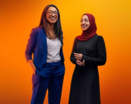 Two female employees in studio with orange background