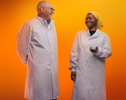 Two scientists posing and talking in front of an orange background