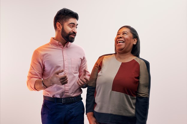 Two employees posing and laughing in front of an white background
