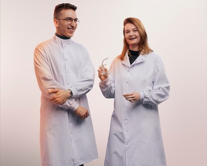 Two scientists posing and smiling in front of a white background