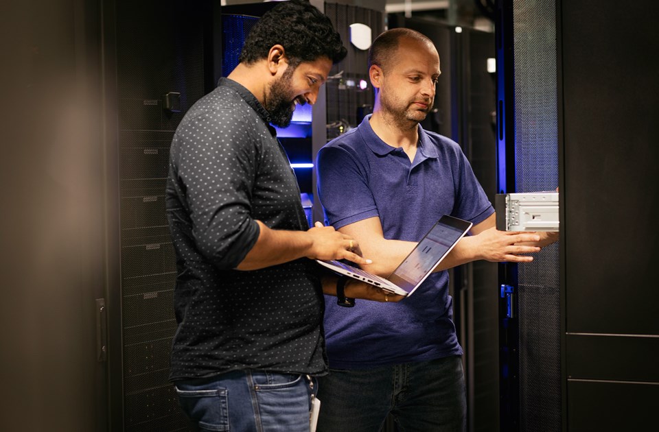 Two male employees smiling and working on machines