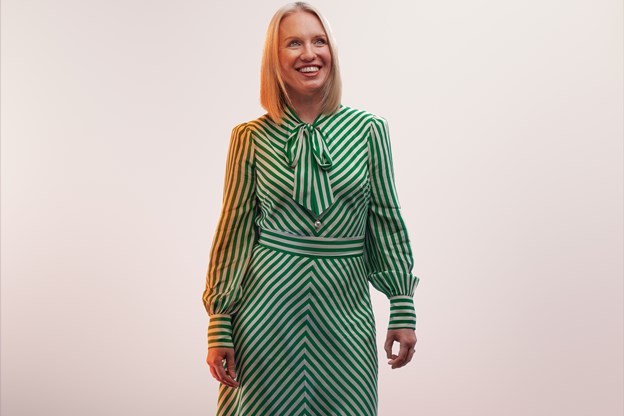 Female employee posing and smiling in front of a white background