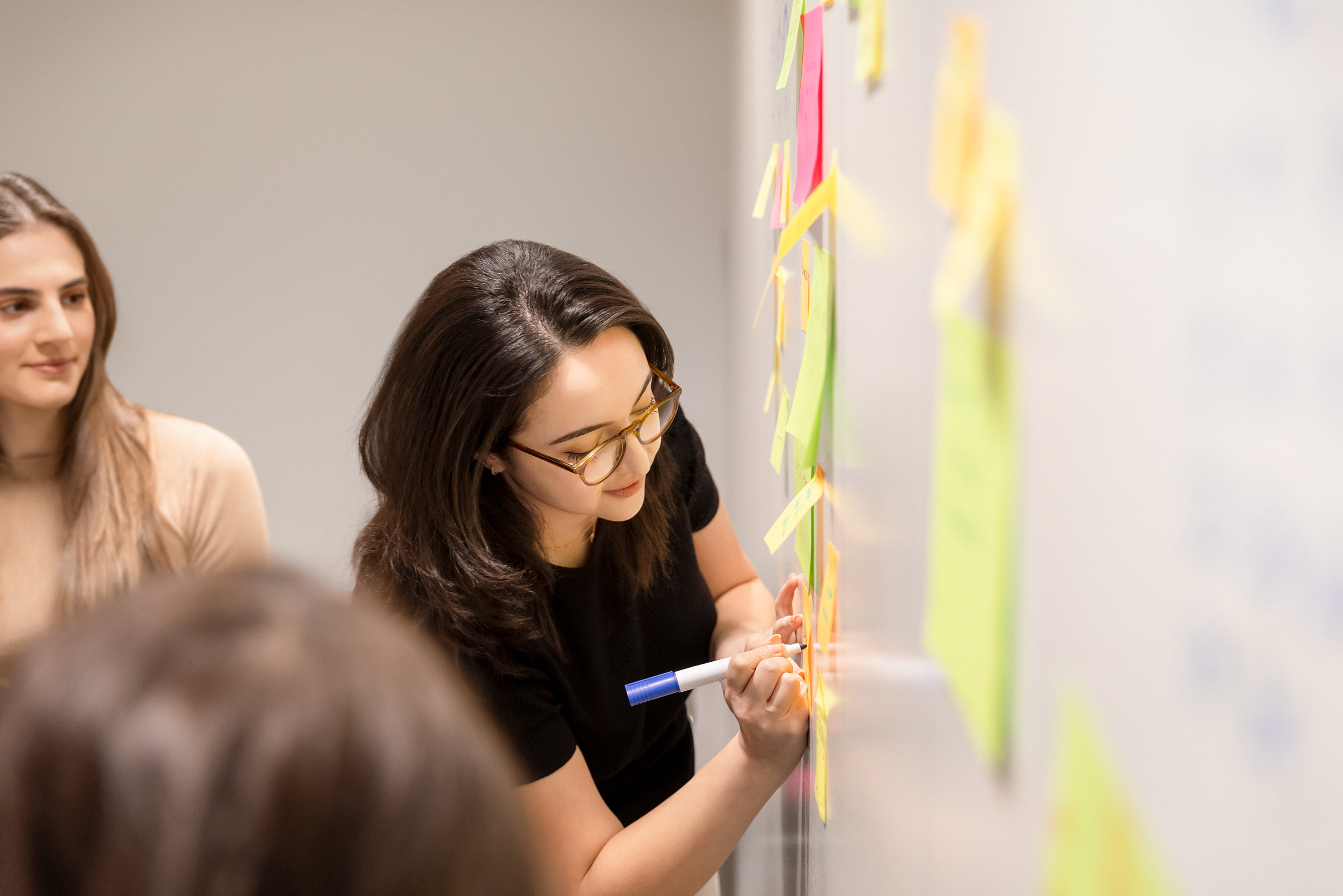 Three female employees brainstorming and writing on a whiteboard