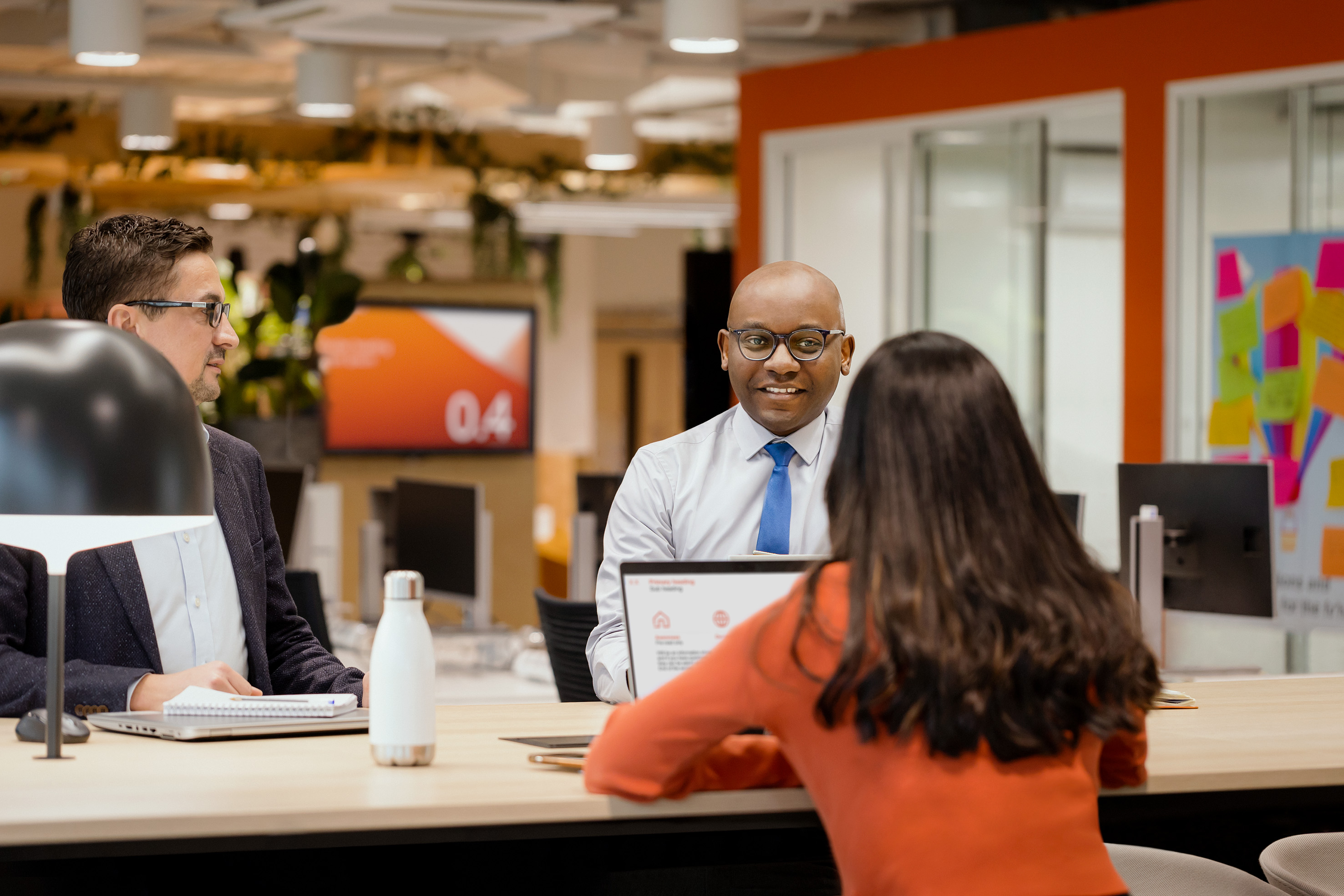 Three employees talking togehter at a desk