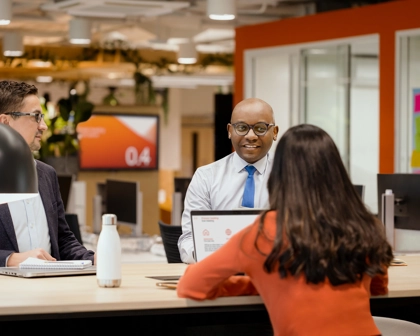 Three employees talking togehter at a desk