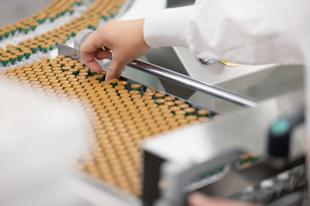 A GSK Wavre employee picking up a vial