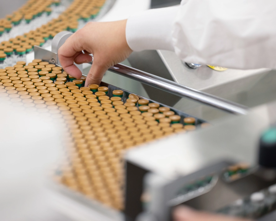 A GSK Wavre employee picking up a vial