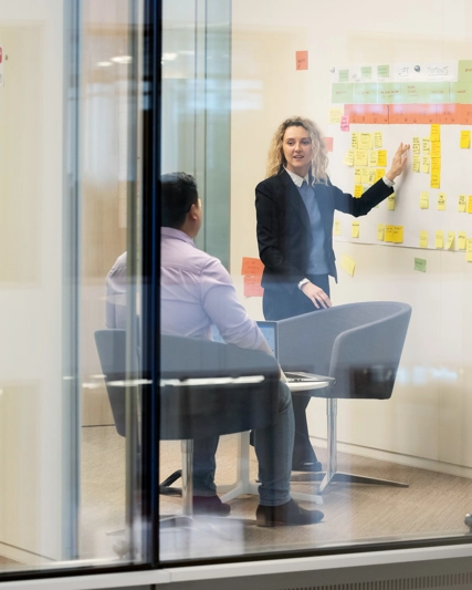 Une femme fait une présentation avec des post-its à son collègue